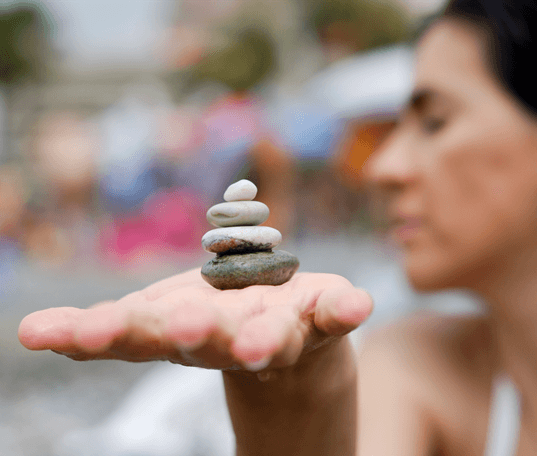 Outstretched hand with small stones stacked upon each other. Native persons profile in the background